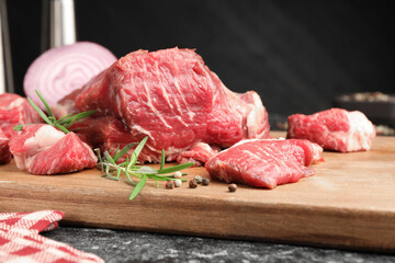 Pieces of raw beef meat and spices on black marble table, closeup