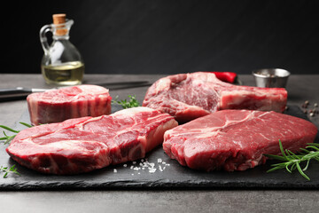 Pieces of raw beef meat and spices on grey table, closeup