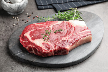 Piece of raw beef meat and spices on grey table, closeup