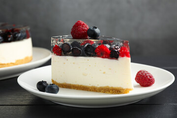 Piece of delicious cheesecake with berries on black wooden table, closeup