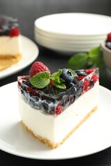 Piece of delicious cheesecake with berries and mint on table, closeup