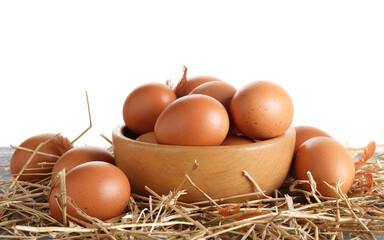 Raw chicken eggs, feathers, bowl and straw on table against white background