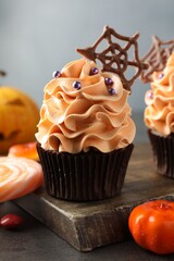 Delicious cupcakes with chocolate web, sprinkles and candies on grey textured table, closeup. Halloween celebration