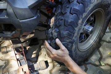 Focused mechanic hand changing large off road tire on vehicle. close up view of hands on process for automotive repair, maintenance, and service on lifted quad bike