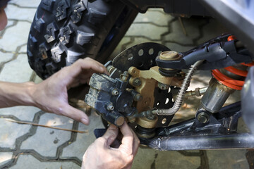 Focused mechanic performing repair and maintenance on an atv vehicle in garage. Close up of hand at work during brake service, showing concentration on task © CoreRock