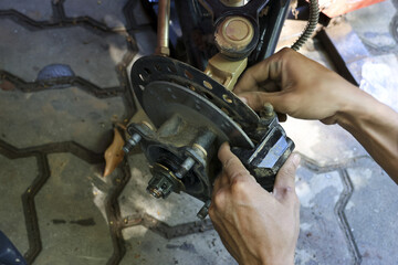 Focused mechanic hand performs motorcycle brake caliper repair and maintenance. skilled man at garage service, assembling and fixing vehicle parts with concentration