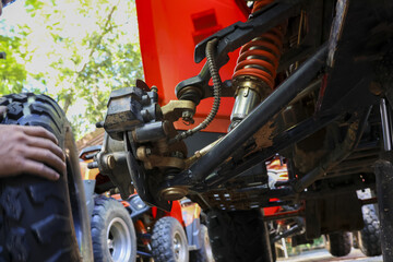 Mechanic performs atv suspension repair and maintenance on an offroad vehicle. Closeup of wheel, shock, and absorber showing detailed work of focused checkup © CoreRock