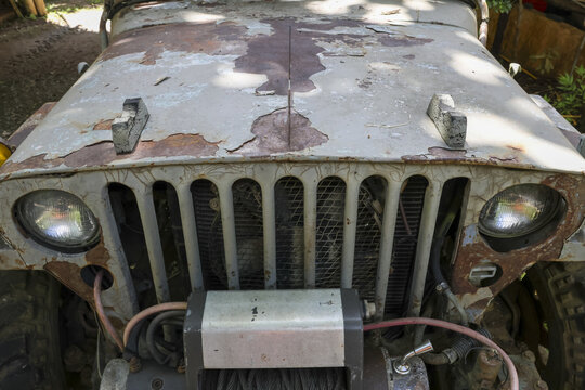 Front view of an old, rusty, vintage off road vehicle showing forgotten classic automobile. weathered grill and nostalgic look tell story of adventure and time