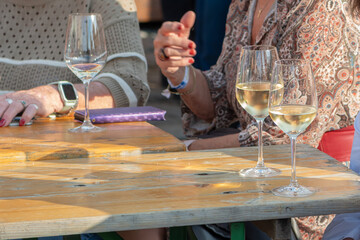 Two women enjoy white wine at a wooden table at a street festival in Retz.