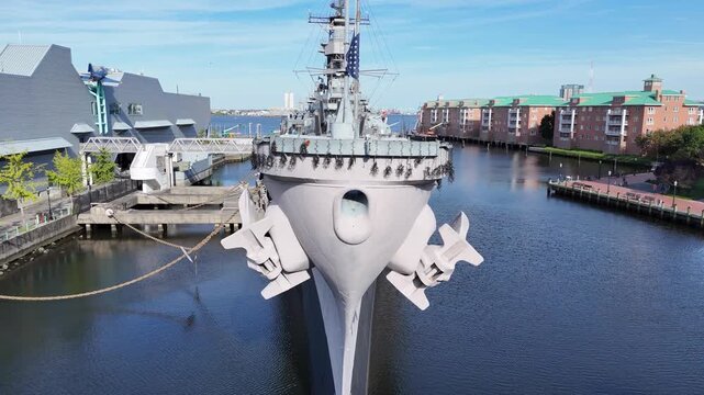 The historic Wisconsin BB-64 battleship sits docked at the Norfolk harbor, featuring multiple gun turrets, radar towers, and a towering superstructure, conveying power, defense, and maritime strength
