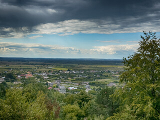 Hilltop view of village under dramatic cloudy sky. Scenic panorama of countryside village before the rain