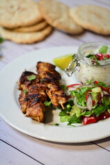 Turkish kebab served on a plate with warm pita bread, accompanied by fresh vegetables and traditional sauces. A delicious and authentic presentation of Middle Eastern cuisine.