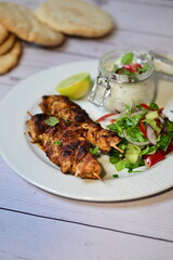 Turkish kebab served on a plate with warm pita bread, accompanied by fresh vegetables and traditional sauces. A delicious and authentic presentation of Middle Eastern cuisine.