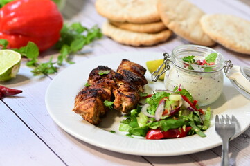 Turkish kebab served on a plate with warm pita bread, accompanied by fresh vegetables and traditional sauces. A delicious and authentic presentation of Middle Eastern cuisine.