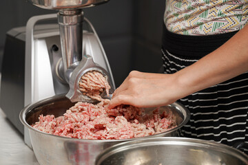 Preparing fresh ground meat using a meat grinder in a modern kitchen during the day