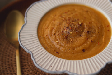 Creamy vegetable soup with chili flakes in a decorative bowl, warm comforting fall meal perfect for cozy homemade dinners - 120 chars -