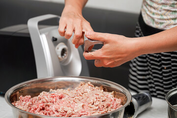 Preparing ground meat for cooking in a kitchen with a food processor and kitchen utensils