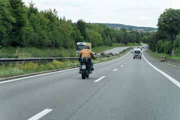 Motorcyclist riding along a scenic highway surrounded by greenery in the countryside during daylight hours