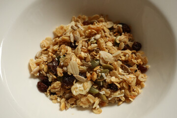 Granola mix filling a bowl, showing healthy breakfast food with nuts, seeds, and raisins. Cotswolds countryside, England