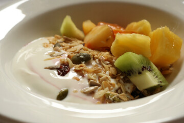 Yogurt with granola, kiwi, pineapple, melon, dried cranberries, and pumpkin seeds. Cotswolds countryside, England