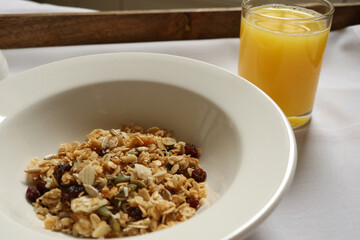 Healthy breakfast meal with muesli, dried fruit, seeds, and nuts refreshing orange juice. Cotswolds countryside, England