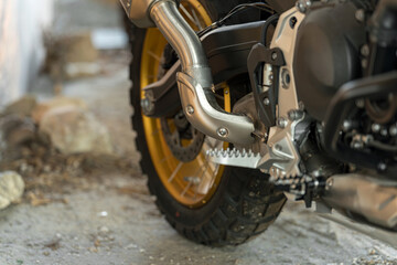 Fototapeta premium Close-up view of motorcycle exhaust and tire on a rugged surface in a garage setting