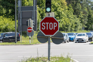 Red stop sign at an intersection with green traffic light on a sunny day in a suburban area © andov