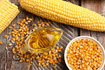 Corn oil, kernels and cobs on wooden table, flat lay
