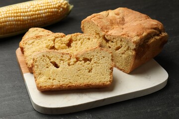 Freshly baked cornbread and cob on black table, closeup