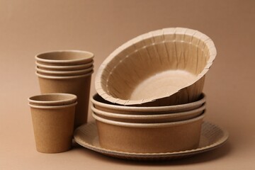 Set of disposable tableware on brown background, closeup