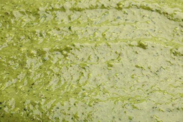 Tasty green pesto sauce as background, closeup