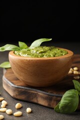Fresh pesto sauce in bowl and ingredients on grey table, closeup