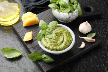 Fresh pesto sauce and ingredients on black textured table