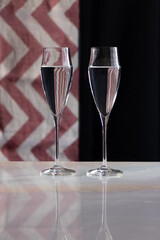 two glasses of champagne on marble table and red and black striped background