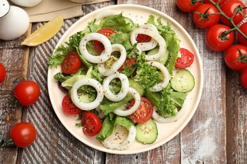 Delicious salad with squid rings, vegetables and spices served on wooden table, flat lay