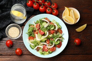 Delicious salad with squid, vegetables and walnuts served on wooden table, flat lay