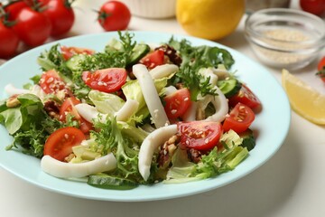Delicious salad with squid and vegetables on white table, closeup