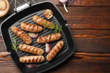 Pan with grilled sausages and spices on wooden table, top view