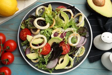 Delicious salad with squid rings and ingredients on light blue wooden table, flat lay