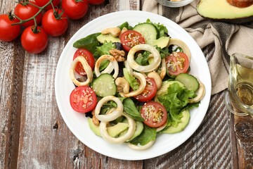 Delicious salad with squid rings and ingredients on wooden table, flat lay