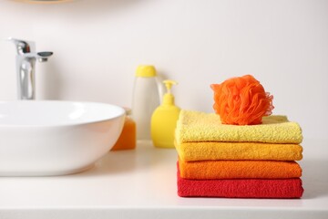 Stack of fresh terry towels and sponge on counter near sink