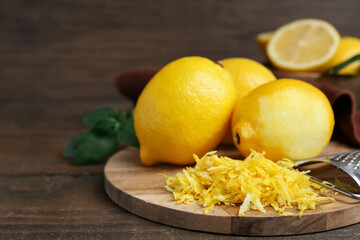 Lemon zest, fresh fruits and grater on wooden table, closeup