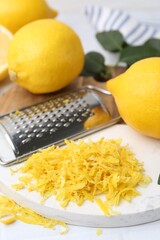 Lemon zest, fresh fruits, grater and green leaves on table, closeup