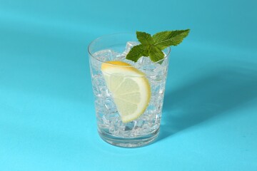 Refreshing water with lemon, mint and ice on light blue background