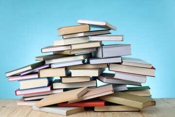 Many books on wooden table against light blue background