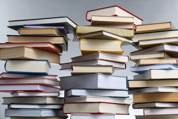 Many stacked books against light grey background, closeup