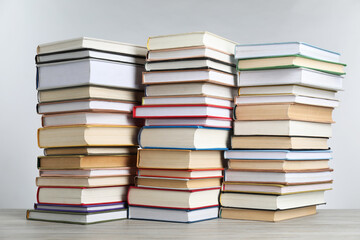 Many stacked books on table against light grey background