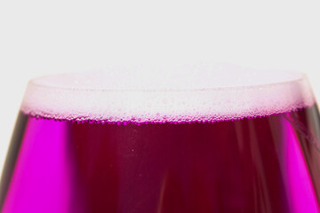 glass with pink liquid on white background