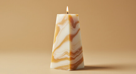 Unique pyramid shaped candle with white and orange marbled wax texture lit with a small flame. Minimalist home decor and aromatherapy concept for cozy atmosphere and stylish interior design on a warm 