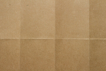 Fototapeta premium Brown kraft paper texture with fold lines. Detailed cardboard surface showing intersecting creases and natural fiber patterns.
